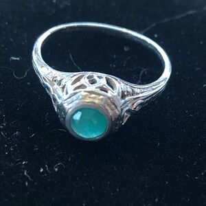 Size 8 filigree design ring displaying a pale emerald colored  stone.
